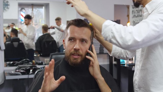 Barber making hairstyle using comb for bearded man