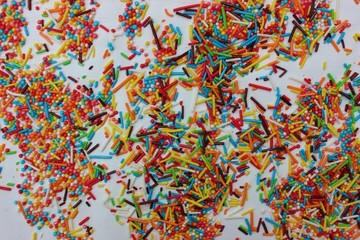 confectionery powder for decorating cupcakes and cakes. Decorative sprinkles border on white background. Multicolor Sugar confectionery powder in the corner. Scattered sweet sugar sticks and balls.