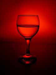 Fototapeta na wymiar Glass of wine on a red background, close-up.