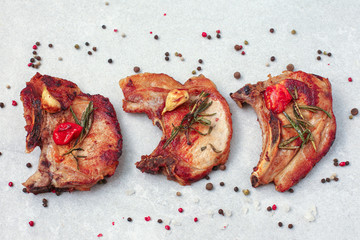 Roasted pork loin steaks with herbs and spices on light background
