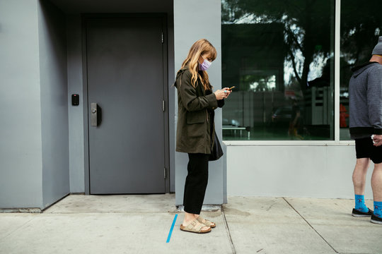 People Using Their Phones And Having Social Distancing While Line Up During Coronavirus Pandemic