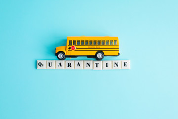 The inscription Quarantine with yellow school bus toy on blue background