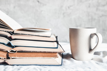 Stack of opened books with a cup of coffee in bed