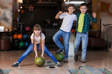 Little children playing bowling in club