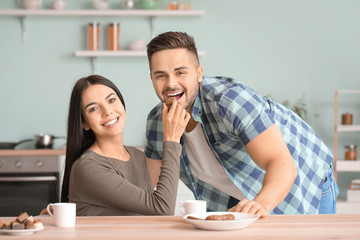 Beautiful young couple eating chocolate in kitchen