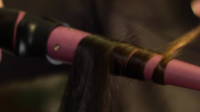 A curl of hair is wound on a curling iron