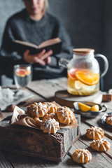 Woman is reading and Hot tea with fresh grapefruit on wooden tablet. Healthy drink, Eco, vegan.