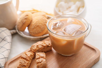 Glass cup of tasty iced coffee with cookies on table