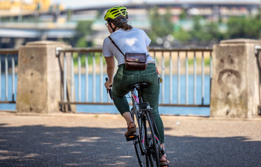 Fototapeta na wymiar Woman with a handbag rides a bicycle along the city promenade preferring an active lifestyle