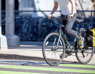 Young man rides a bicycle across the road in a dedicated lane for cyclists at a pedestrian crossing