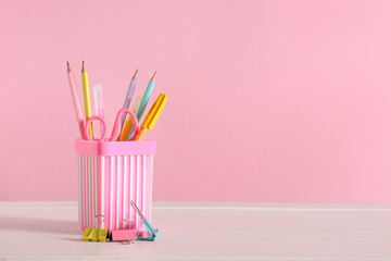 Holder with stationery on table against color background