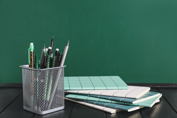 Holder with stationery on table near blackboard © Pixel-Shot