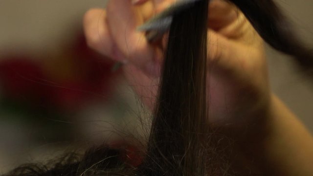The stylist holds in her hands a strand of hair of a girl
