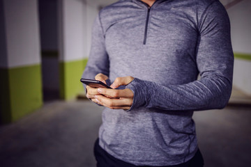 Closeup of young muscular man using smart phone.