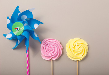 Pink, yellow Rose candy  with Colorful toy windmills in pastel colors on a wooden stick on a grey  background, Valentine, Mother's Day.