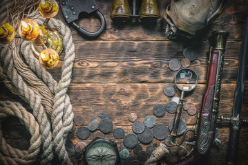 Pirate treasure chest with ancient coins and other various pirate equipment on flat lay table...