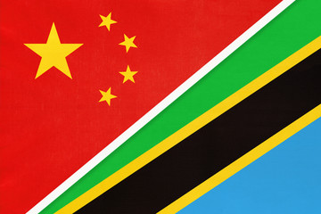 China or PRC vs Tanzania national flag from textile. Relationship between Asian and African countries.