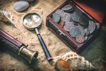 Pirate treasure chest with ancient coins and other various pirate equipment on flat lay table...