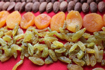 Almonds, raisins and dried apricots laid out by a line on a red background. Almonds, dried apricots...
