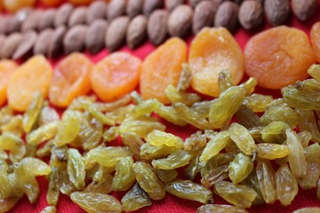 Almonds, raisins and dried apricots laid out by a line on a red background. Almonds, dried apricots and raisins close-up with place for text. Nuts and dried fruits, healthy nutrition.