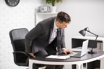Young man suffering from hemorrhoids in office