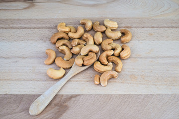Roasted cashew nuts on wooden spoon and wooden table, healthy snack, vegetarian food