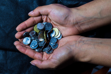 HANDS GIVING COINS IN A DARK BACKGROUND