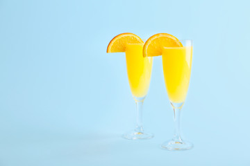 Glasses of tasty mimosa cocktail on color background
