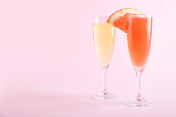 Glasses of tasty mimosa cocktail and champagne on color background