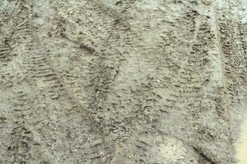 Dirty dirt road with track, wheel marks, brown clay and puddles in Russia.