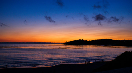 Fototapeta na wymiar The sun setting over the horizon at a beach in Carmel Ca.