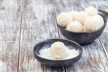 Healthy raw paleo energy coconut balls in ceramic bowl, horizontal, copy space
