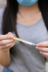 Obraz premium Asian woman wearing face protection Holding a thermometer Temperature measurement,Virus mask,Healthcare and sickness prevention from coronavirus, Covid19,Selective of focus.