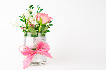 Small vase with pink bow and rose flowers, white background with copy space