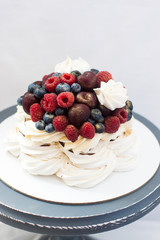 Meringue Pavlova cake with chocolate sauce, whipped cream and fresh cherries, strawberries, blueberries.