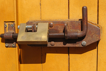 Rusty old latch and padlock on a door