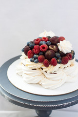 Meringue Pavlova cake with chocolate sauce, whipped cream and fresh cherries, strawberries, blueberries.