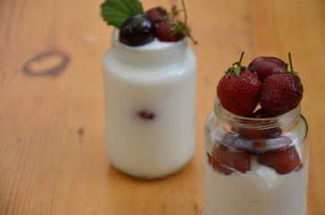 Healthy breakfast home made pudding or yogurt or granola, strawberries, cherry, berry,  yogurt in a bowl. Vegetarian concept food. pudding or cocktail on of green foliage