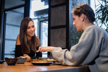 Two girlfriends chatting and having some snacks in a cafe