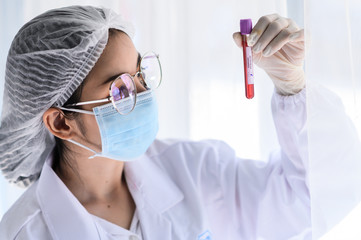 coronavirus covid 19 infected blood sample in sample tube in hand of scientist with biohazard...