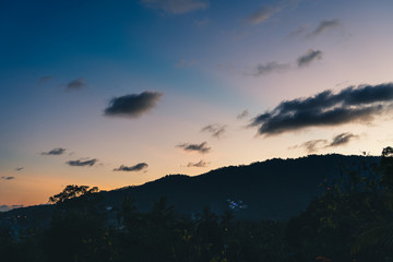 Fototapeta na wymiar Sunset over trees, sea and mountains on a tropical island