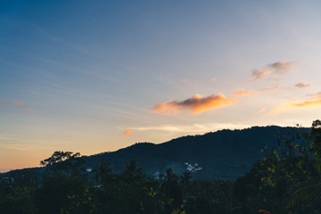 Sunset over trees, sea and mountains on a tropical island