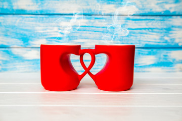 two heart shaped mugs with tea on blue background
