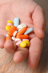Several colored tablets in hand close-up. Concept of assistance in case of illness. Help with viral infection.