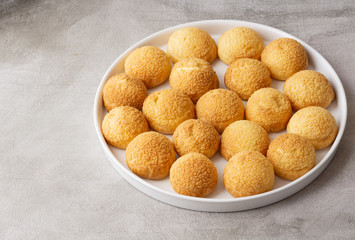 Chou pastry biscuits in a white plate on grey background. Concept: bakery, french dessert. 