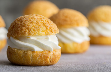 Chou pastry biscuits filled with whipped cream on grey background. Concept: bakery, french dessert....