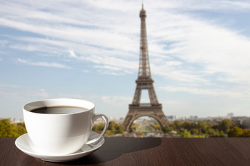 Fototapeta na wymiar Cup of coffee on the table with view of Eiffel tower in Paris, France
