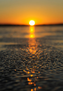 Reflejo del sol en el mar durante un atardecer con cielo de color anaranjado.
