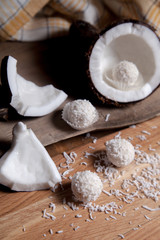 Close up of coconut with white pulp, coconut chip and white candies on wooden background..