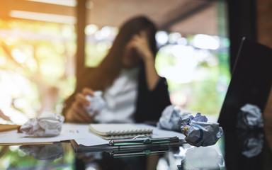 Businesswoman get stressed with screwed up papers and laptop on table while having a problem at...